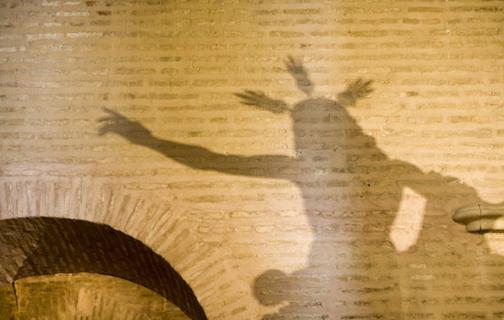 The shadow of a Resurrected Jesus Christ image on a wall of Santa Marina church, Seville, Spain