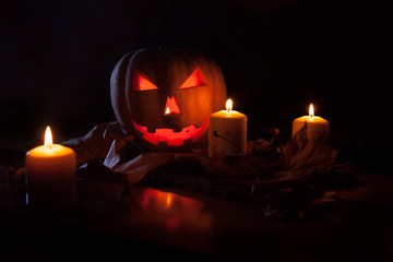 Calabaza de Halloween rodeada con grandes velas iluminando su terrorífica expresión