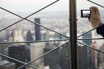 A visitor taking a picture of NYC from the top of the Empire State Building