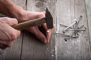 Hammer in a man's hand to hammer in nails on the wooden background