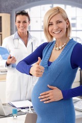Happy pregnant businesswoman at doctor's office