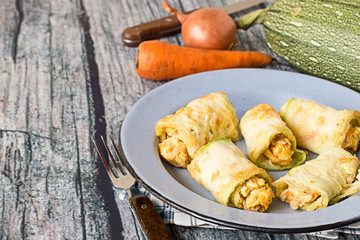 Rolls from zucchini.   Rolls from zucchini in a metal bowl, fresh vegetables, fork and knife on old wooden table.