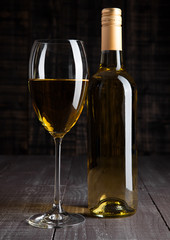 Bottle and glass of white wine on wooden board