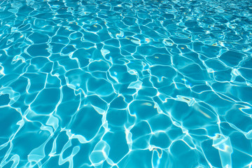 Fototapeta na wymiar Blue water surface with sun reflection in swimming pool