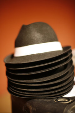 Stack of black hats against a red background