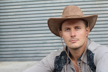 Portrait of serious young cowboy with hat isolated on textured gray background with copy space 