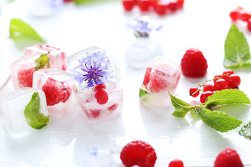 Ice cubes with raspberries and mint leaf on wooden table