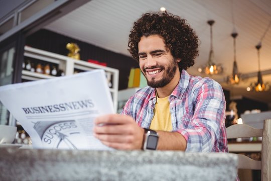 Man smiling while reading newspaper