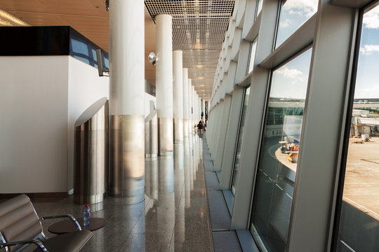 Airport corridor along transparent glass wall with window