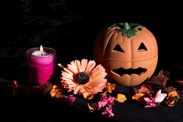 halloween pumpkin with dried flowers potpourri and tea light on black background