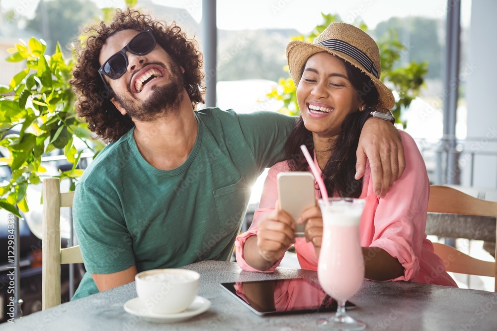 Poster couple having fun while using mobile phone