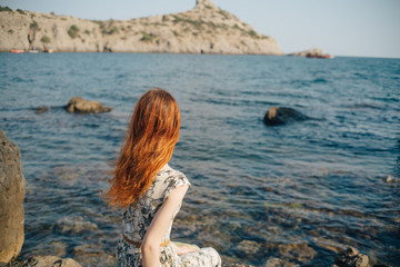 Fototapeta na wymiar woman on the beach, sitting on a rock Woman, long hair in dress