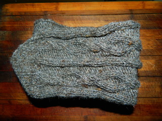 Grey knitted sock with a large pattern on a wooden board