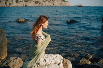 woman on the beach, sitting on a rock Woman, long hair in dress