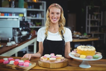Portrait of smiling waitress standing with dessert