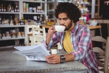 Man reading newspaper while having coffee