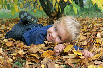 Little Toddler white boy lying on his stomach on the yellow autu