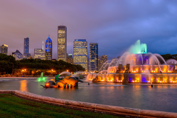 Naklejka premium Panoramę Chicago z drapaczami chmur i fontanną Buckingham w Grant Park nocą oświetloną kolorowymi światłami.