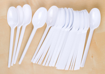 Plastic disposable white spoons on a wooden table