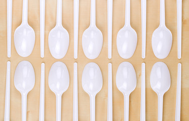 Plastic disposable white spoons on a wooden table