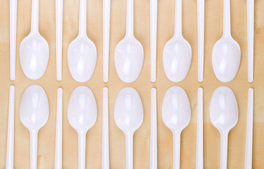 Plastic disposable white spoons on a wooden table