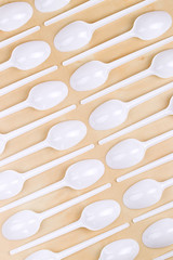 Plastic disposable white spoons on a wooden table
