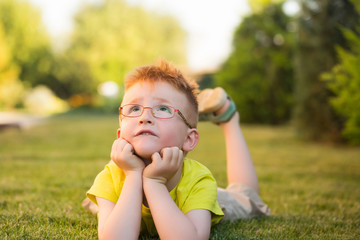 baby boy with red hair in glasses on grass