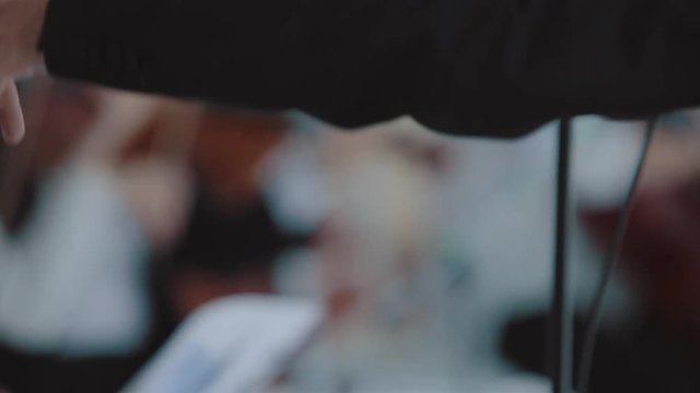 the conductor's hand with a stick on classical orchestra, closeup