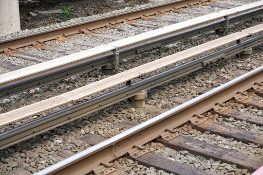 An overhead photo of the dangerous high voltage electrified third rail along railroad train tracks which powers the engine of commuter trains