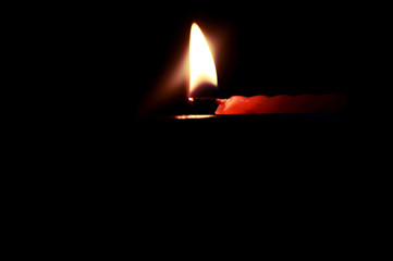 Red candle flame burning bright in black background