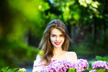 pretty smiling girl in hydrangea flowers