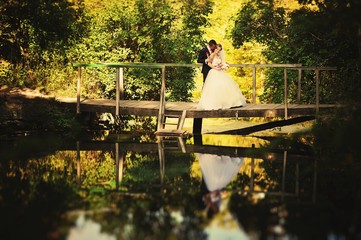 Wedding couple on forest bridge at autumn sunny day