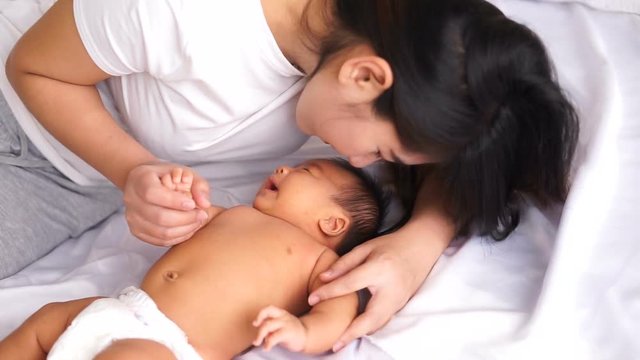 asian young pretty mother kissing her little baby with love