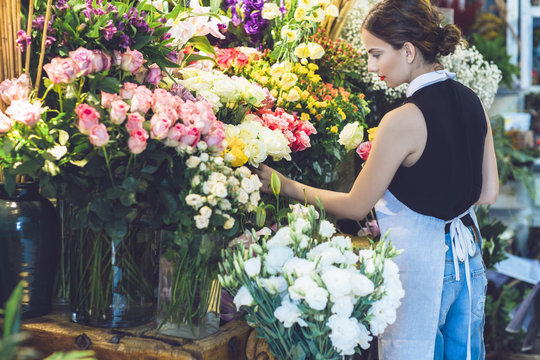 Rear view of female florist picking roses from potted plants
