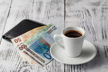 euro bill and cup of coffee on wooden table. Payment, tip.