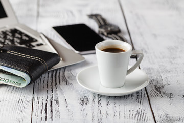 Coffee cup with phone and leather wallet on table