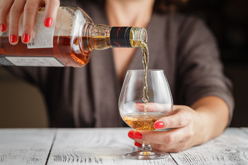 Alcoholism start. Female take wine glass on dark toned table