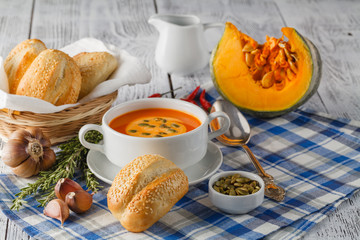 Creamy pumpkin soup topped with pumpkin seeds and cream in a whi