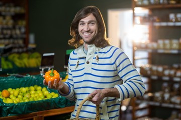 Man with a basket selecting bell pepper in organic section