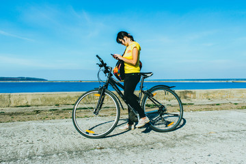 Obraz premium Outdoor portrait of pretty young girl riding bike and talking on the phone.