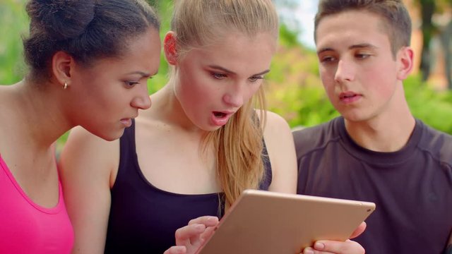 Young friends reading bad news on tablet. Closeup of young people shocked by news in internet. Worried people looking at tablet computer. Emotions of friends reading shocking news on tablet computer