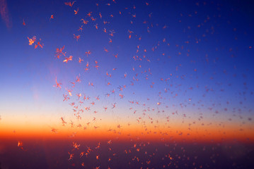 ice crystal sparkling on the window glass of air plane against dawn sky