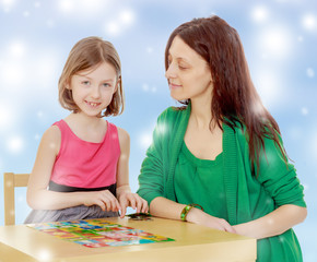 Fototapeta premium The teacher and the girl at the table studying the cards