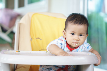 Asian baby eating food by himself