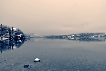 Snowy winter landscape on the lake in black and white, on a cloudy, foggy day. Monochrome image filtered in retro, vintage style with soft focus and red filter. Lake Bohinj, Slovenia - 123013771