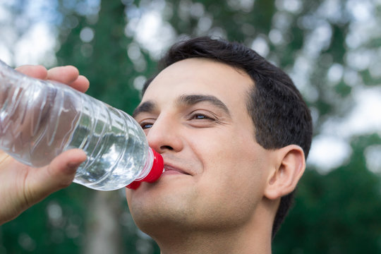 Young fitness man drinks water during training