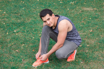 Young fitness man ties up bootlaces on his sport sneakers