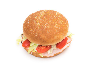 Wholemeal hamburger bun with ham, salad, tomatoes and mayonnaise on white background seen obliquely from above