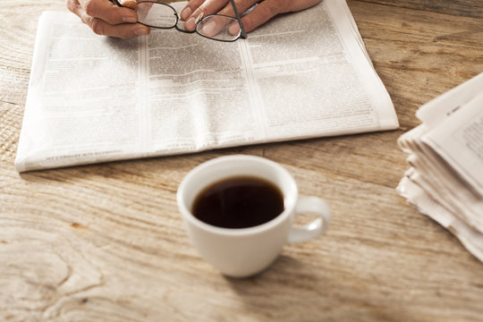 Man reading newspaper with coffee