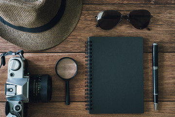 Black notebook with copyspace and retro camera on wooden backgrond